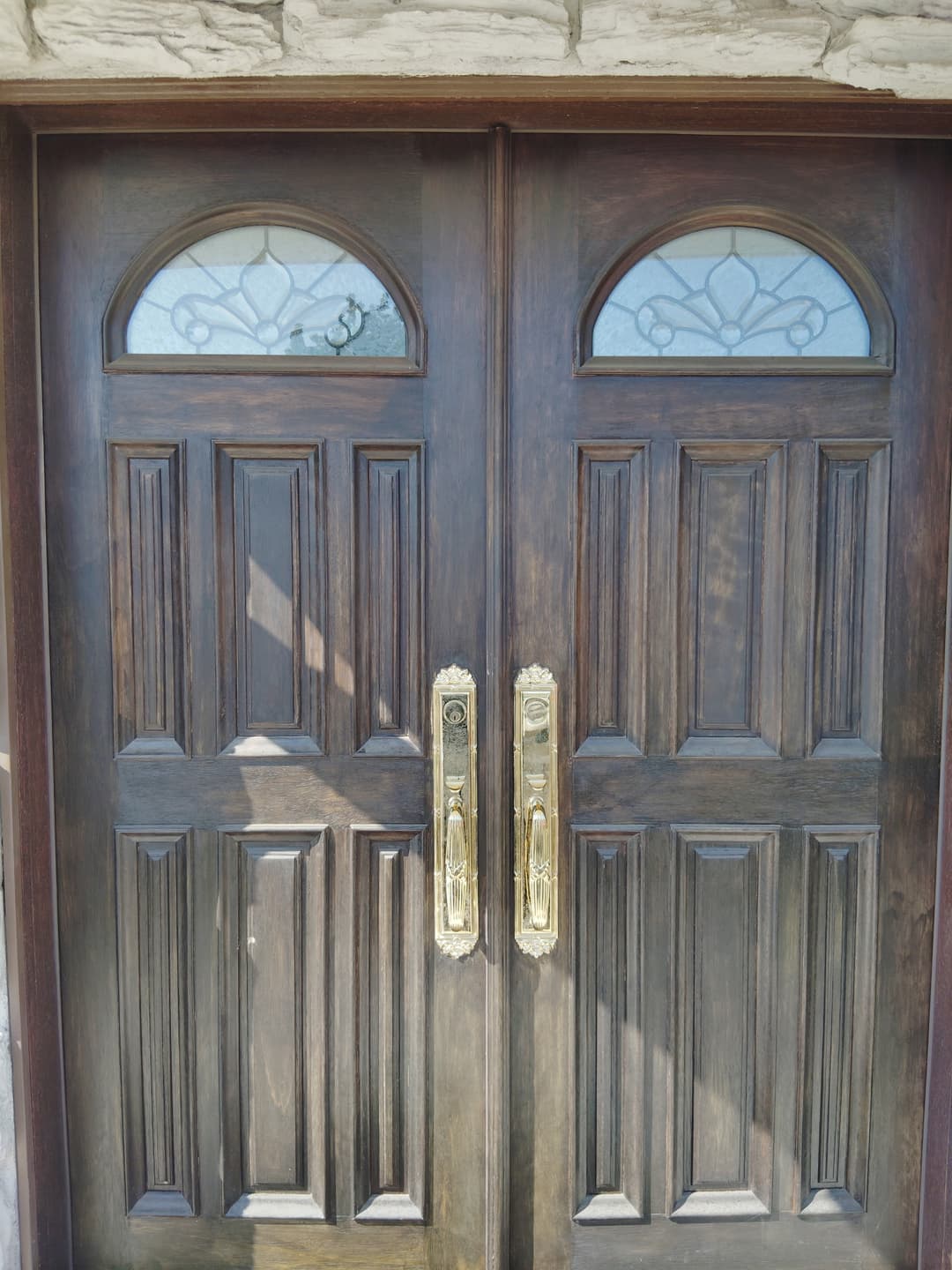 Dark wood double entry doors with decorative glass panels before refinishing